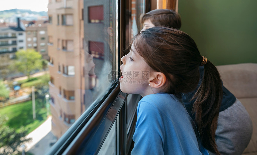 两个孩子一边在玻璃上喘气一边看着窗子图片