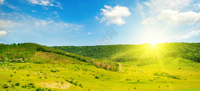 小山上绿草地蓝天太阳图片