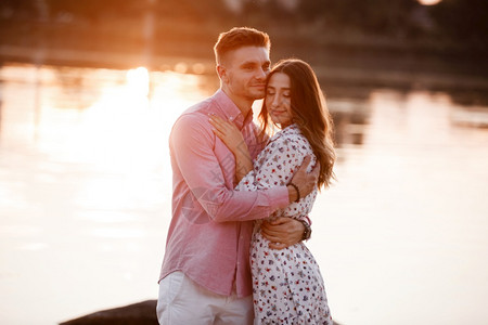 情侣在日落时的湖边拥抱图片