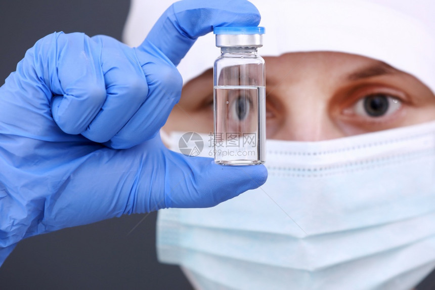 研制和在玻璃瓶中由医生手持的科罗纳疫苗用于戴医疗面具和蓝手套的医生防治科罗纳疫苗概念研制和在玻璃瓶中由戴医疗面具和蓝手套的医生持图片
