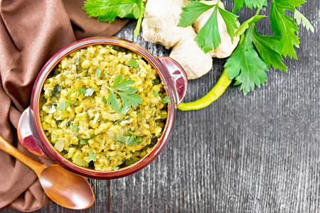 土制的印度全国豆大米菜菠辣椒和香料碗餐巾纸姜和勺子黑木板底来自上方图片