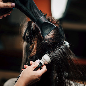 理发师卷着妇女长黑发有刷子和吹风机理发师制造现代型图片