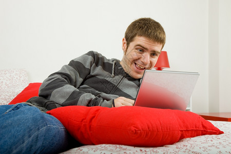 在床上操作计算机的青年临时工图片