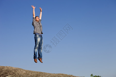 年轻快乐的男孩跳跃在岩石顶上图片