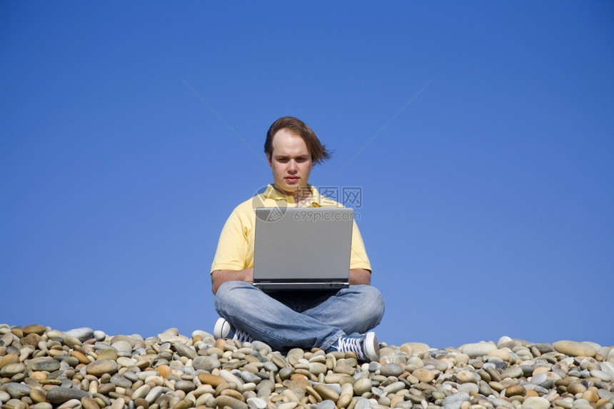 海滩上拿着笔记本电脑的青年男图片