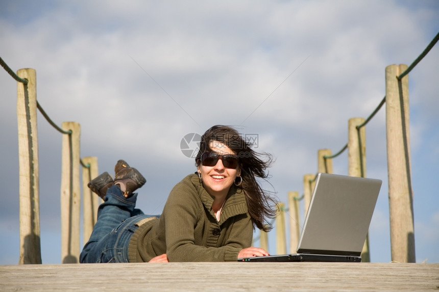 在海滩从事计算机工作的年轻妇女图片
