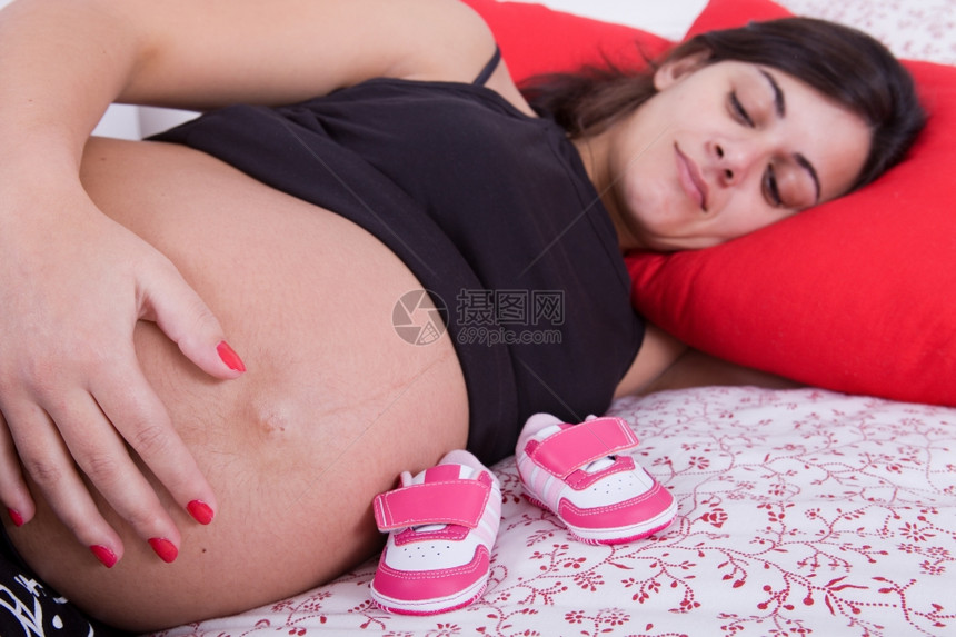 在床上的年轻孕妇专注于肚子图片