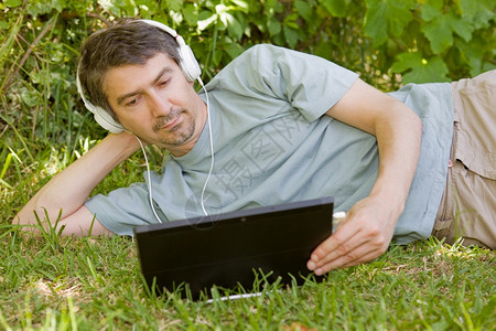 年轻人在户外用平板和耳机放松图片