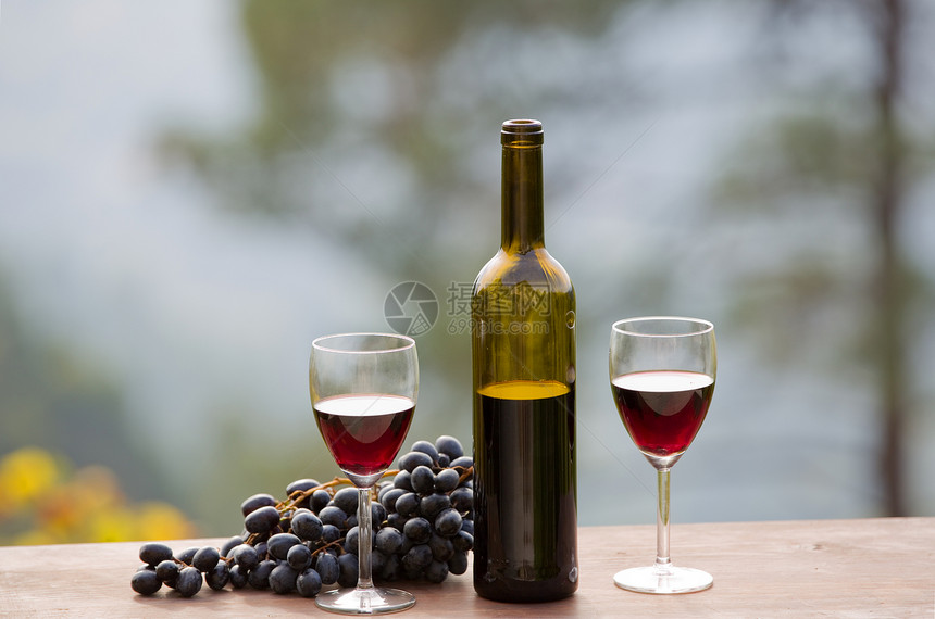 户外木制桌上的酒瓶和葡萄图片