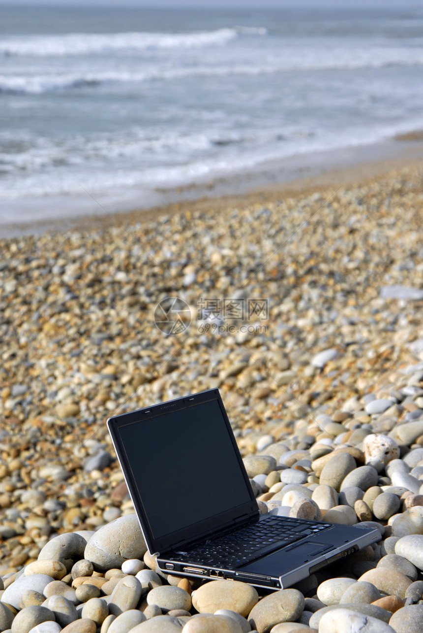 海滩岩石上的现代黑笔记本电脑图片