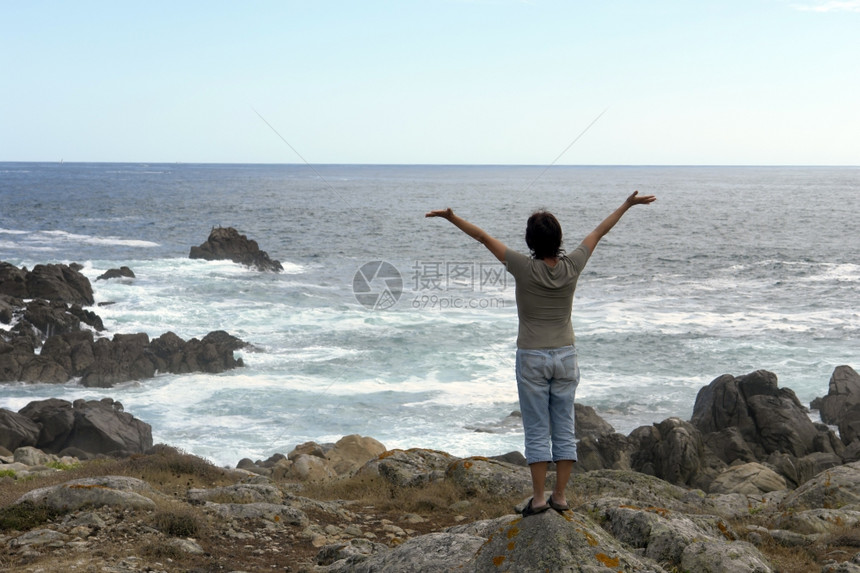 在海岸开阔的双臂张幸福女子图片