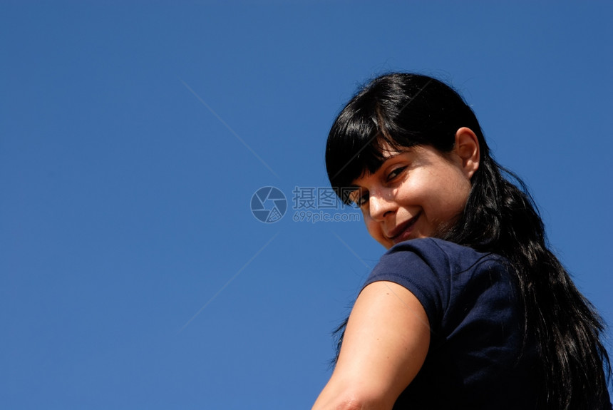 以天空为背景的年轻女子图片