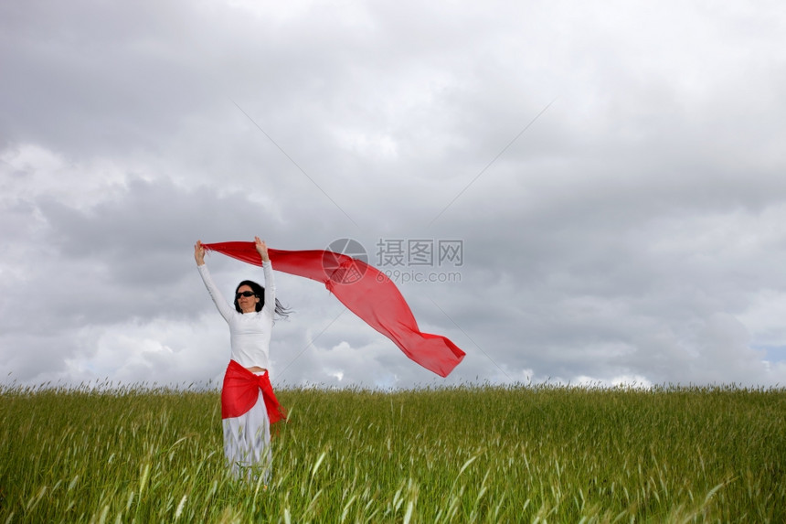 穿着红色围巾在田地上美丽的年轻女士图片