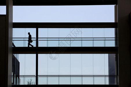 年轻商人在现代办公楼内用全景窗走动的影视背景图片