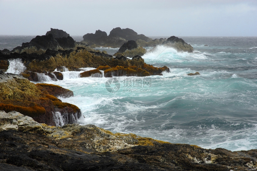 海岸的岩石上有海浪的图片