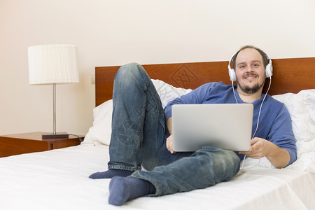 男人在床上用笔记本电脑工作图片