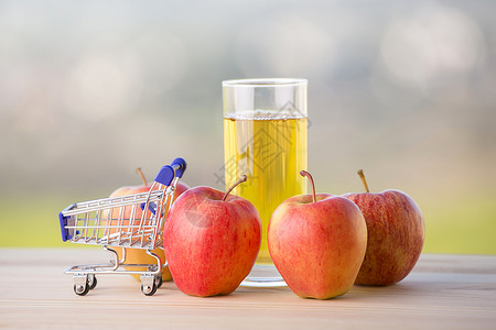 苹果和汁在户外的木制桌子上用购物车图片