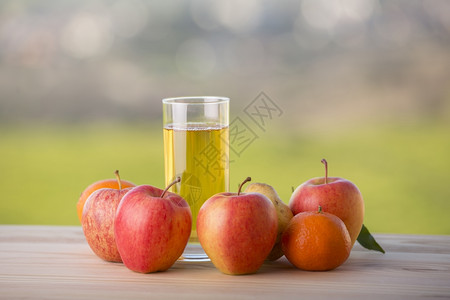 在户外木桌边的水果和苹汁图片