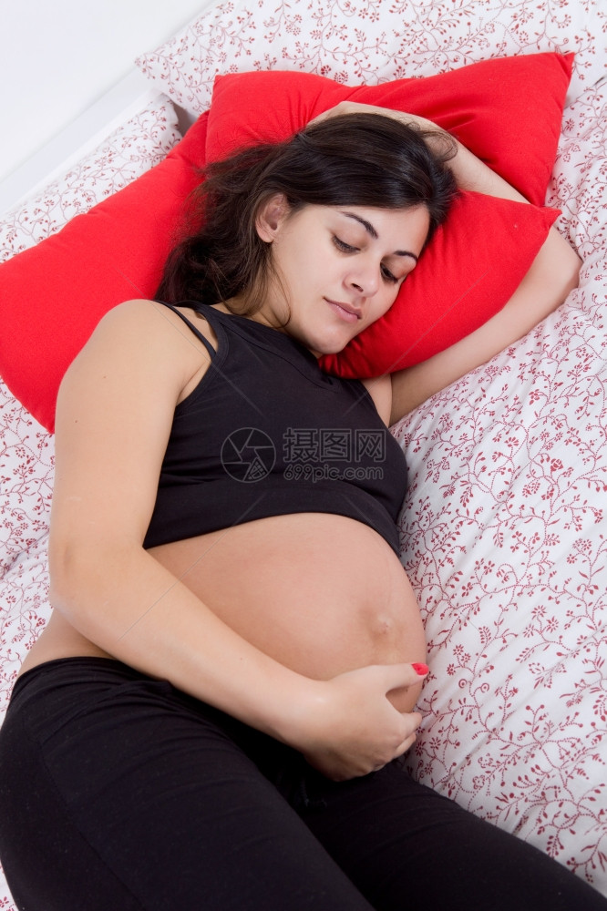 床上的年轻孕妇关注面孔图片