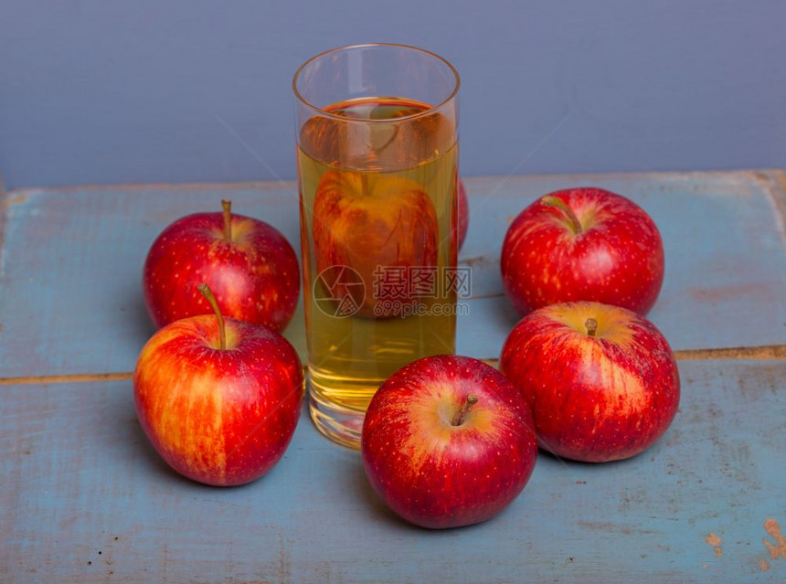 一杯苹果汁红在蓝色的旧木本底图片
