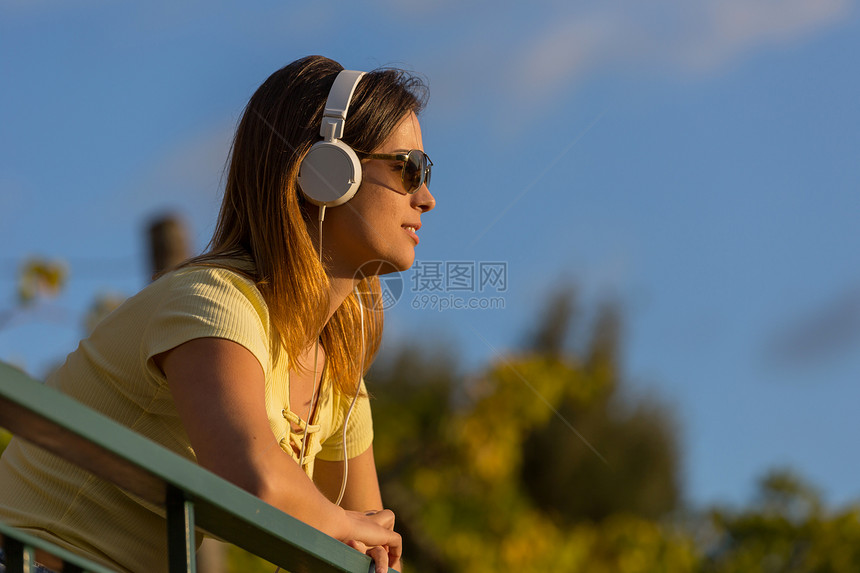 美丽的临时女在日落享受音乐用耳机在户外放图片