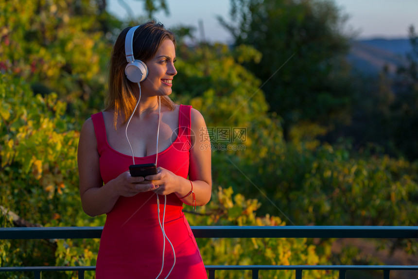 美丽的临时女在日落享受音乐耳机在户外享受音乐图片
