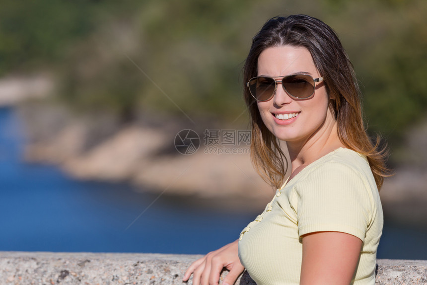 坐在岩石山上放松和享受湖水的快乐年轻女士在古尔斯公园的Gers女孩享受湖水图片