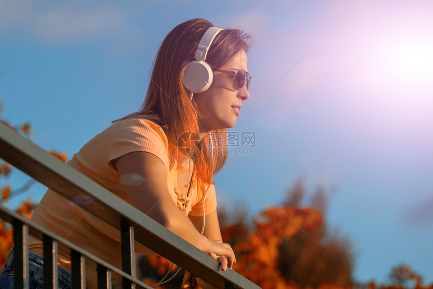 美丽的临时女在日落享受音乐用耳机在户外放图片