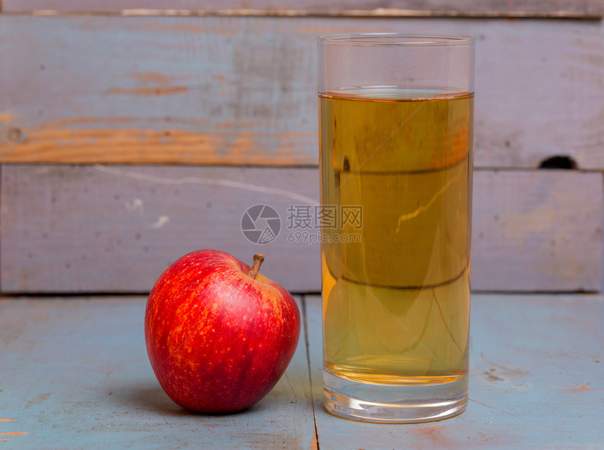一杯苹果汁和红在蓝色的旧木本底图片