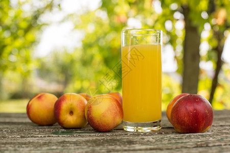户外木桌上的油桃和油桃汁图片