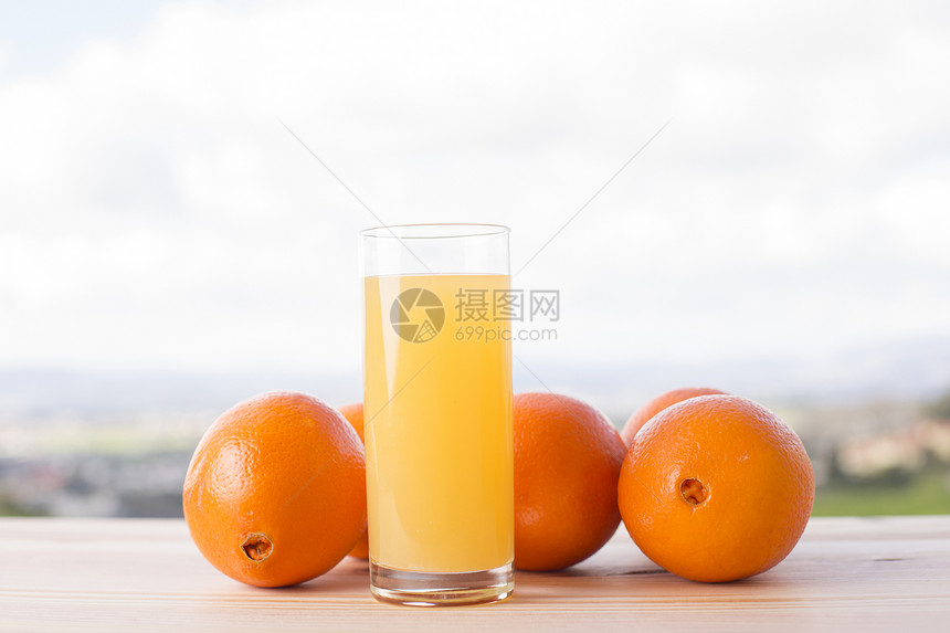 户外木桌上的橙子和橙汁图片