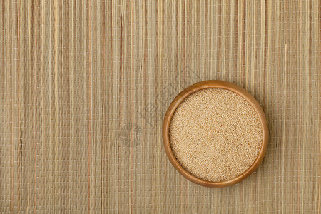 草垫上一小碗木质的阿玛兰特颗粒图片