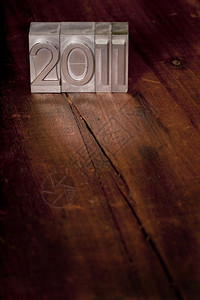 201年新概念旧金属纸质印刷板在深黑的木表面有刮痕和裂缝背景图片