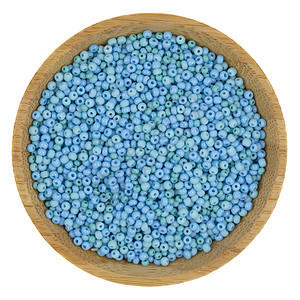 漂浮蓝色珠子一个小木碗上的玻璃珠子以白色隔绝背景