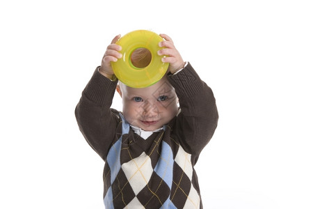 托德勒男孩正在展示一个塑料黄色玩具环图片