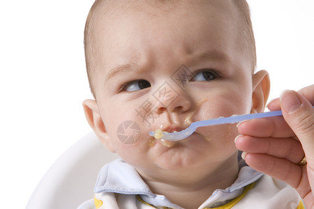 宝男孩用勺子喂饱了宝男孩并有一个不满的表情图片