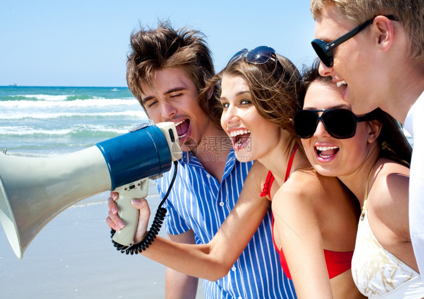 快乐的年轻夫妇在夏天沙滩上用扩音机喊叫图片