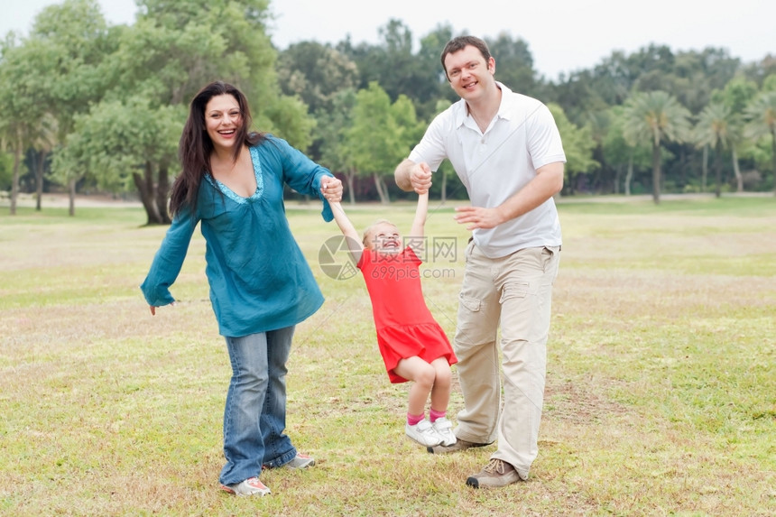 快乐的一对夫妇在绿色公园玩耍和他们美丽的女儿一起度过自然背景图片
