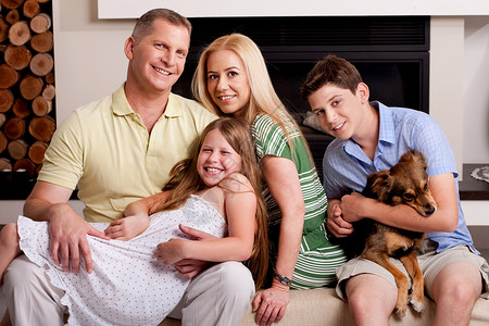 小男孩抱着狗在客厅里和家人一起拍照图片