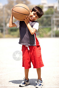 肩膀上打篮球的男孩户外图片