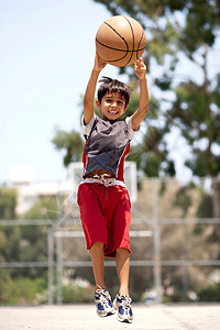年轻篮球运动员在投时高空跳跃图片