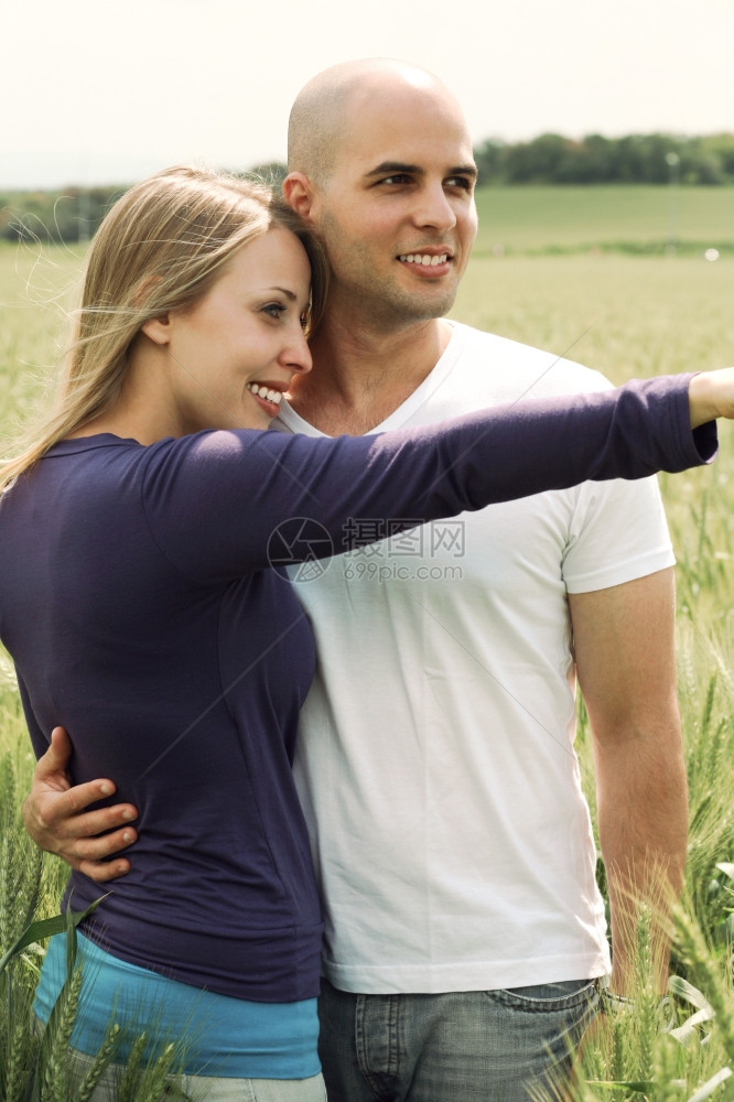 在草地的年轻夫妇双手在空中拥抱公园里图片