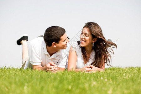年轻情侣躺在草地上约会图片