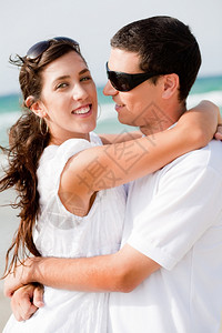 浪漫情侣的肖像热地拥抱在海滩外的门图片