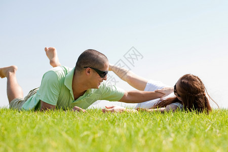年轻男子与妻在草坪上玩耍躺下图片