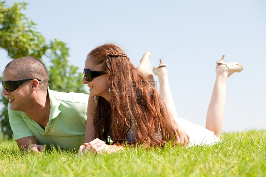 美丽的年轻夫妻躺在草地上微笑着图片