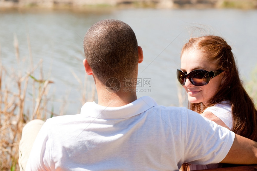 坐在湖边的年轻夫妇后视线以女为焦点图片
