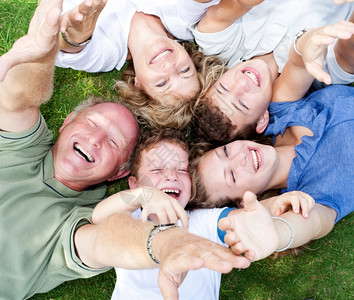 幸福的家庭躺在公园圆圈里举起手来图片