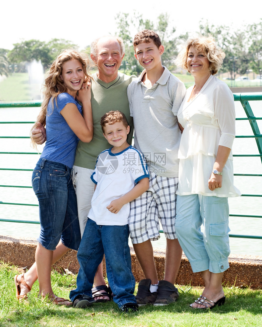 在阳光明媚的一天幸福家庭在湖边摆姿势图片