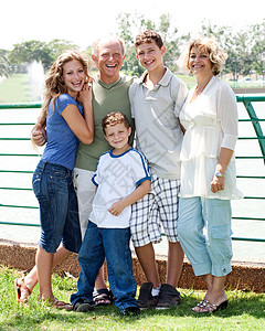 在阳光明媚的一天幸福家庭在湖边摆姿势图片